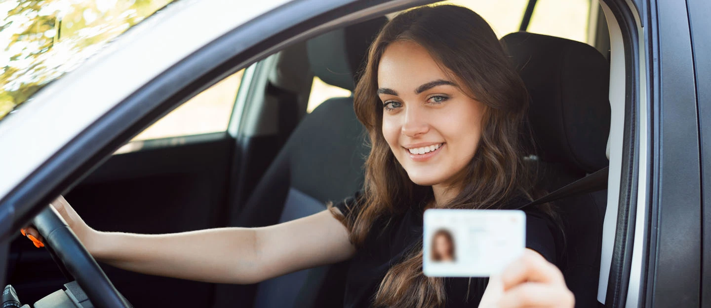 Smiling driver in a car holding a document